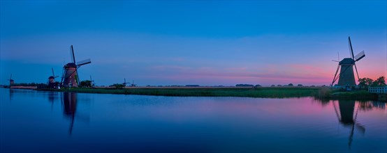Panorama of Netherlands rural landscape with windmills at famous tourist site Kinderdijk in Holland in twilight