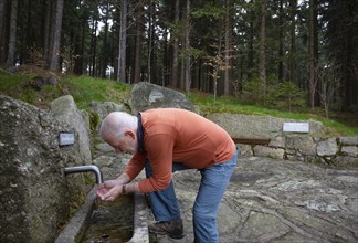 Hiker refreshes himself at the spring water fountain at the 1000 m square
