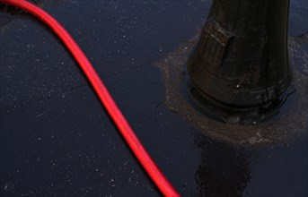 Red water hose on wet asphalt