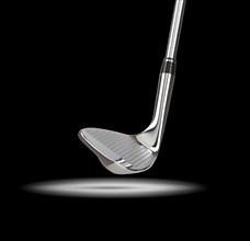 Chrome golf club wedge iron under spot light with black background