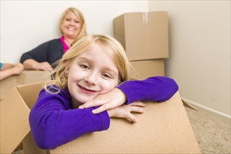 Happy young mother and daughter having fun with moving boxes