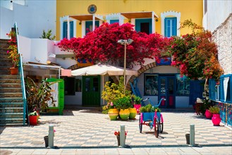Picturesque street with colorful houses and blooming bougainvillea flowers in Adamantas town on Milos island in Greece