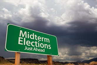 Midterm elections green road sign over dramatic clouds and sky
