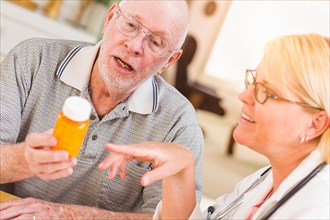 Doctor or nurse explaining prescription medicine to attentive senior man