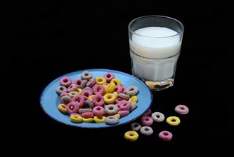 Fruit-flavoured cereal rings in plate and glass of milk