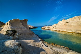 White rocks of famous tourist attraction of Milos island Sarakiniko beach with tourist relax and Aegean sea