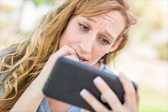 Concerned young woman outdoors looking at her smart phone