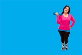 Middle aged hispanic woman in workout clothes holding dumbbell against A bright cyan blue background