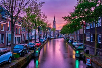 Canal with parked along cars in Delft town in evening dusk after rain
