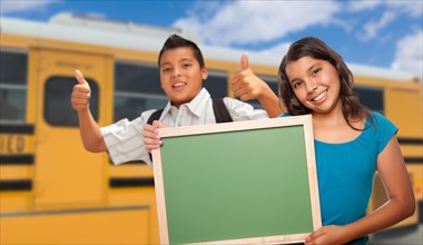 Young hispanic students with blank chalkboard near school bus
