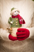 Woman wearing seasonal red mittens holding christmas snowman