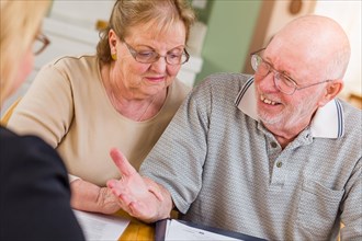 Senior adult couple going over documents in their home with agent at signing