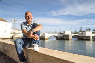 Portrait of smiling man relaxing by the riverbank in touristic and historic Tavira