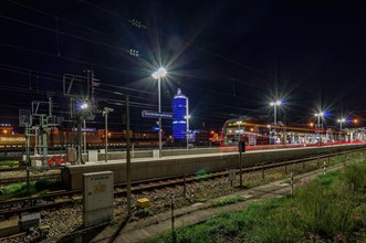 Arriving S-Bahn as long exposure at night in front of blue luminous tower