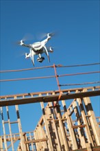 Drone quadcopter flying and inspecting wood framing at construction site