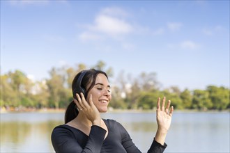 Young woman listening to music outdoors with bluetooth headphones. Expression of happiness