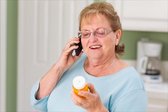 Senior adult woman on cell phone holding prescription bottle