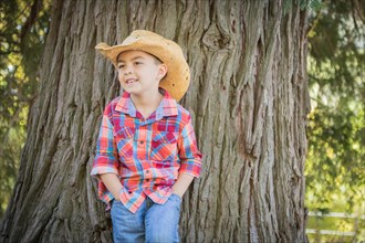 mixed-race young boy wearing cowboy hat standing outdoors