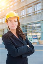 Portrait of young attractive professional female contractor wearing hard hat at construction site