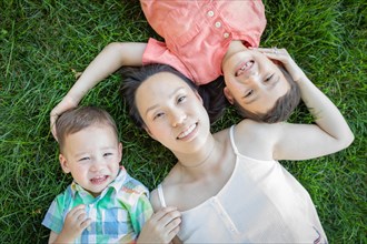 Chinese mother and mixed-race children laying on grass