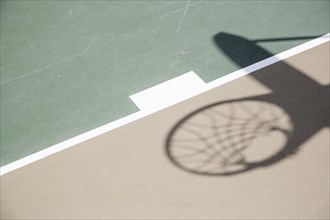 Abstract shadow of basketball hoop and net against court surface