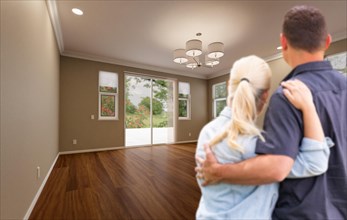 Young adult couple looking at empty room of new house
