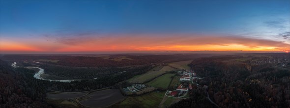 Orange glowing sunset behind Schaeftlarn Monastery and the meandering Isar River