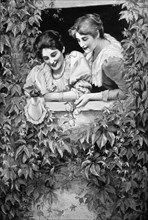Two women in a window surrounded by a bush looking towards the street