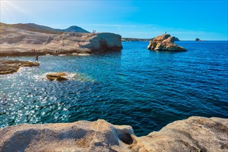 White rocks of famous tourist attraction of Milos island Sarakiniko beach with tourist relax and Aegean sea