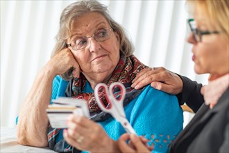 Financial consultant handing scissors to senior lady holding credit cards