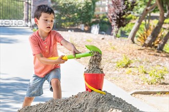 Young caucasian and chinese boy playing with shovel and bucket