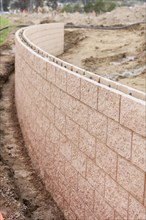 Curved new outdoor retaining wall being built at construction site
