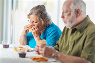 Senior adult couple enjoying sandwiches at table