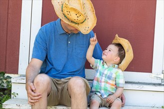 Playful young caucasian father and mixed-race chinese son wearing cowboy hats