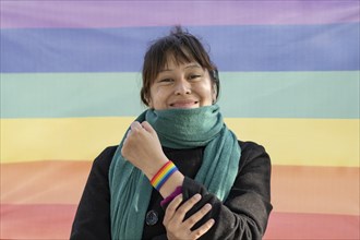 Portrait of a lesbian latin woman wearing lgbt wristband on a rainbow background