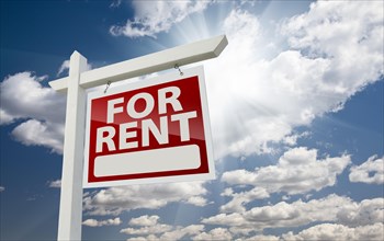 Right facing for rent real estate sign over clouds and sunny sky with room for text