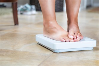 Woman standing on scale at home covering weight results with toes