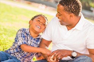 African american father and mixed-race son playing with baseball in the park