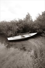 Fischerboot im Morgennebel im Schilfguertel am Ufer