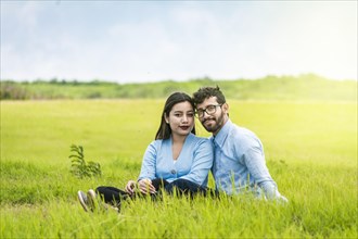 Portrait of a couple in love sitting on the grass in the field
