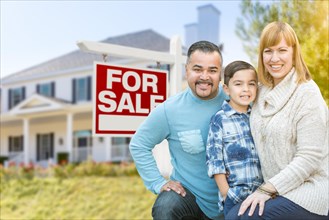 Happy mixed-race hispanic and caucasian family portrait in front of house and sold for sale real estate sign