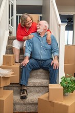 Senior couple resting on stairs surrounded by moving boxes