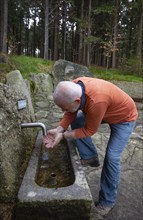 Hiker refreshes himself at the spring water fountain at the 1000 m square
