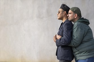 Gay latin couple wearing fashionable hats hugging in the street. Copy space