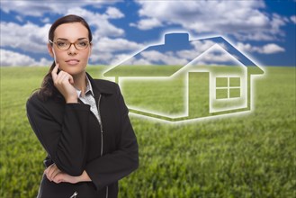 Smiling woman in grass field with ghosted house figure behind