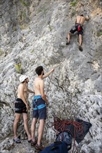 Young man belays a climber on lead