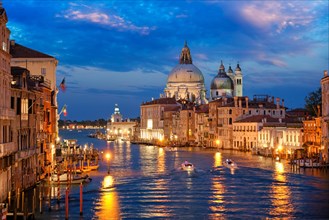 View of Venice Grand Canal with boats and Santa Maria della Salute church in the evening from Ponte dell'Accademia bridge. Venice