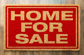 Home for sale welcome mat on A wood floor background