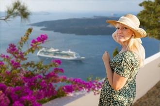 Attractive female tourist admiring the view of the cruise ship off the coast of santorini Greece