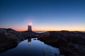 Lighthouse surrounded by rocks at night